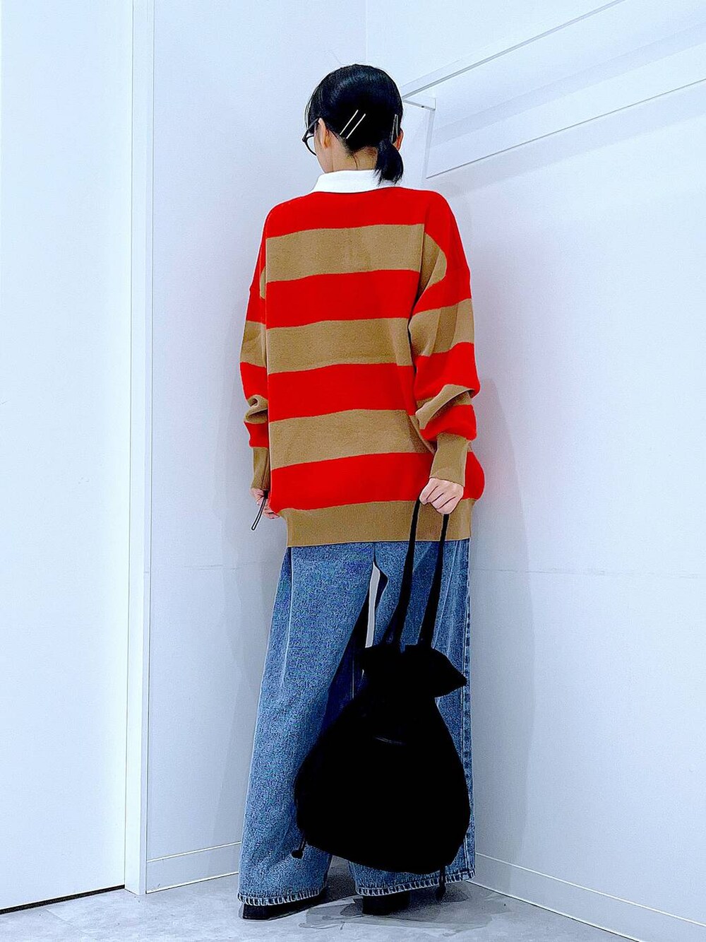 ブラック系のトートバッグ、レッド系のニット/セーター、ブルー系のデニムパンツを着用したレディースの冬コーディネートの5枚目の写真