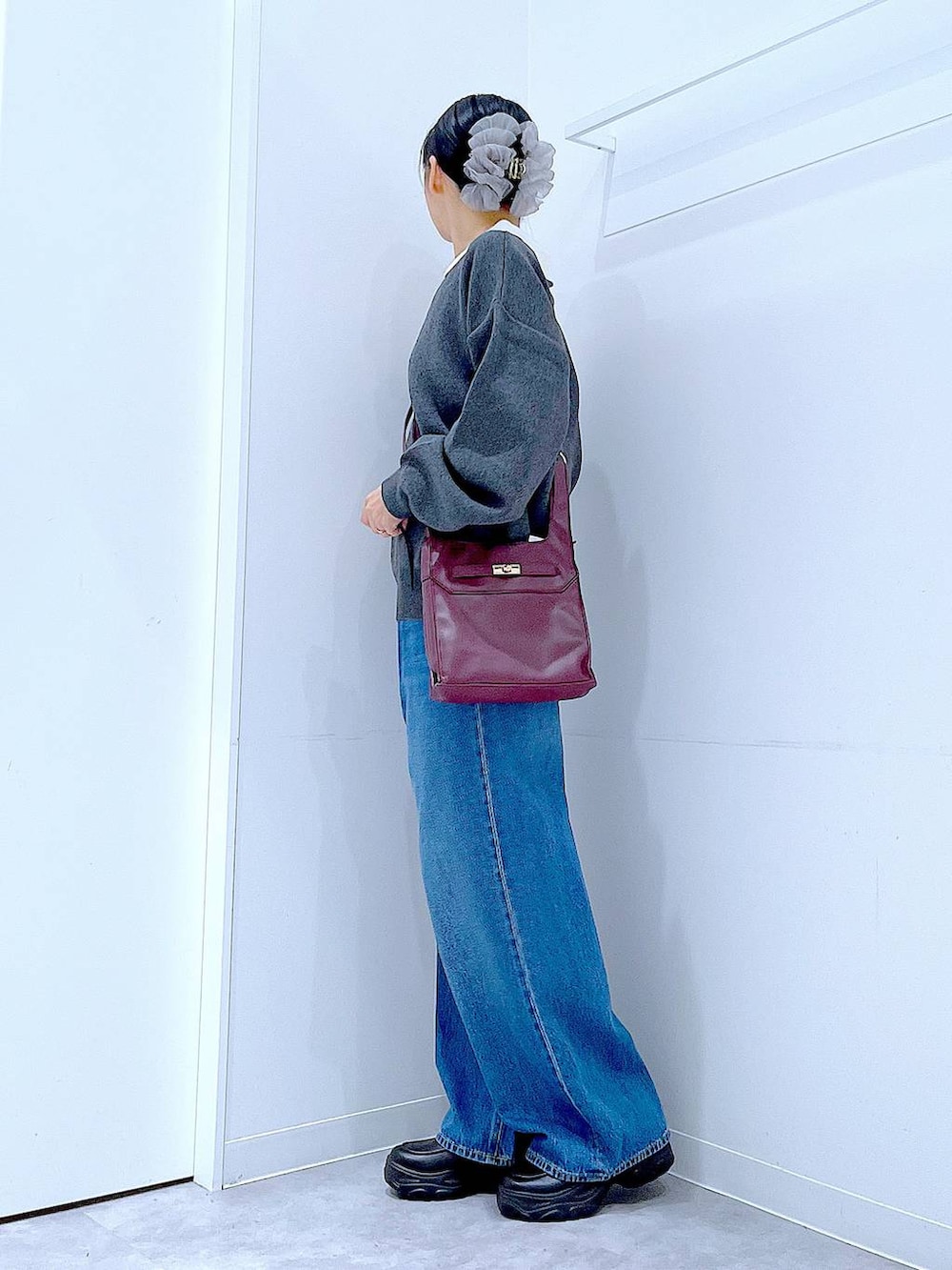 ブルー系のデニムパンツ、レッド系のショルダーバッグ、グレー系のニット/セーターを着用したレディースの秋コーディネートの3枚目の写真