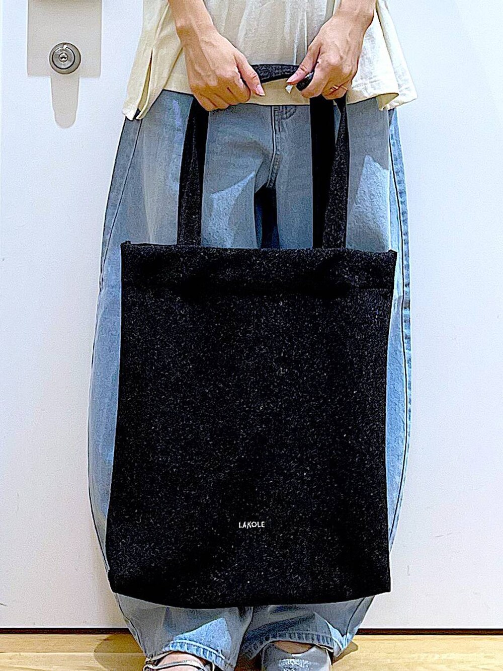 ブラック系のトートバッグ、ブルー系のデニムパンツ、シルバー系のパンプスを着用したレディースの夏コーディネートの9枚目の写真