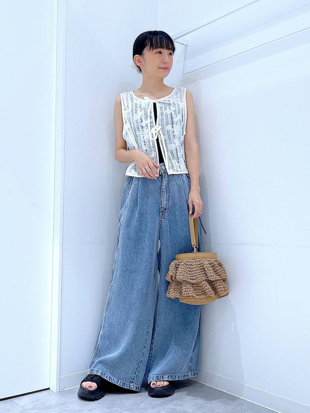 ベージュ系のショルダーバッグ、ブルー系のデニムパンツ、ベージュ系のベストを着用したレディースの夏コーディネートの2枚目の写真