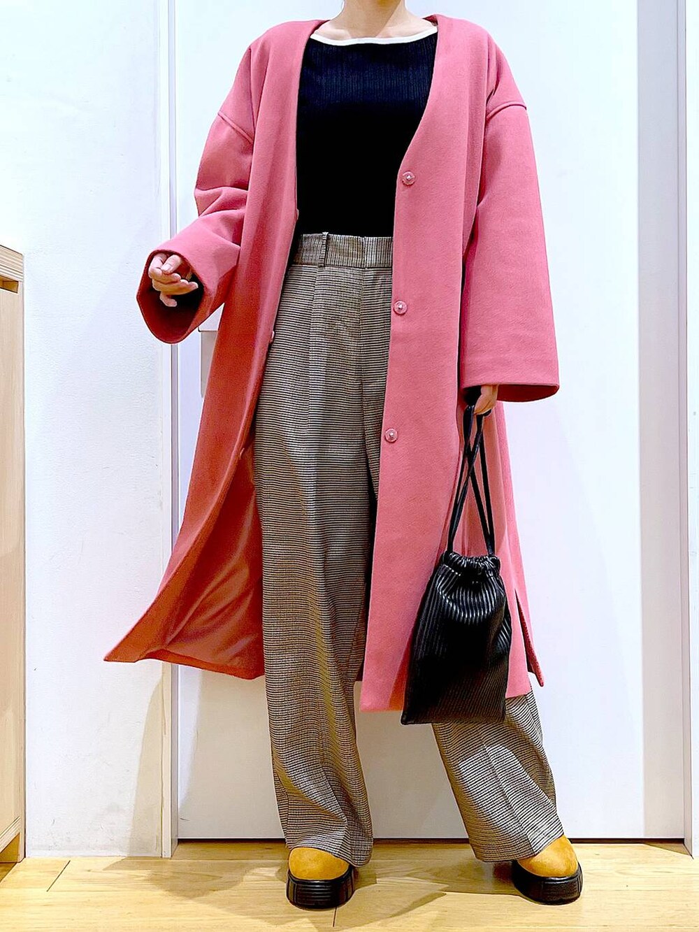 ブラック系のショルダーバッグ、ブラック系のニット/セーター、ベージュ系のスラックスを着用したレディースの冬コーディネートの6枚目の写真