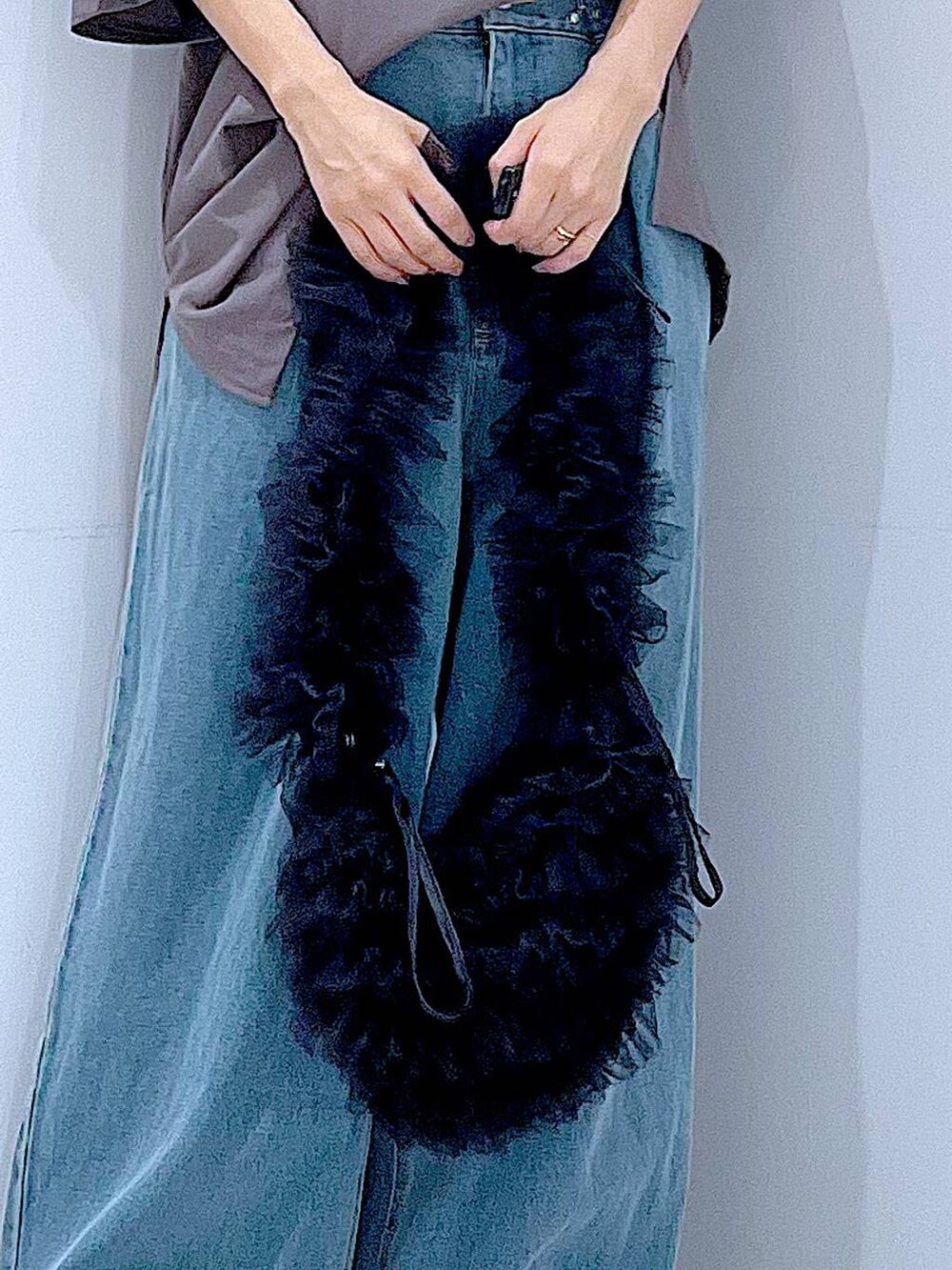 ブラック系のショルダーバッグ、ブラック系のスニーカー、ブルー系のデニムパンツを着用したレディースの秋コーディネートの9枚目の写真