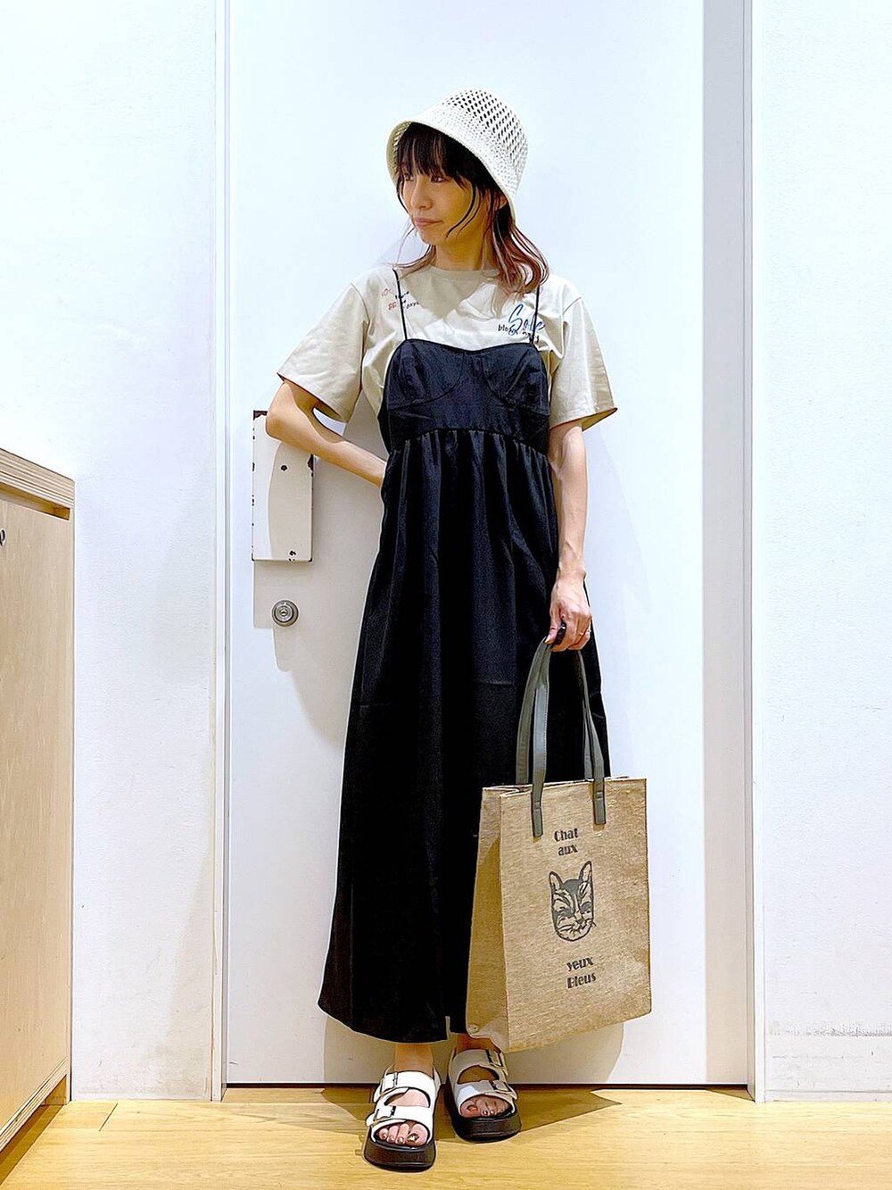ホワイト系のサンダル、グレー系のトートバッグ、ブラック系のワンピースを着用したレディースの夏コーディネートの2枚目の写真