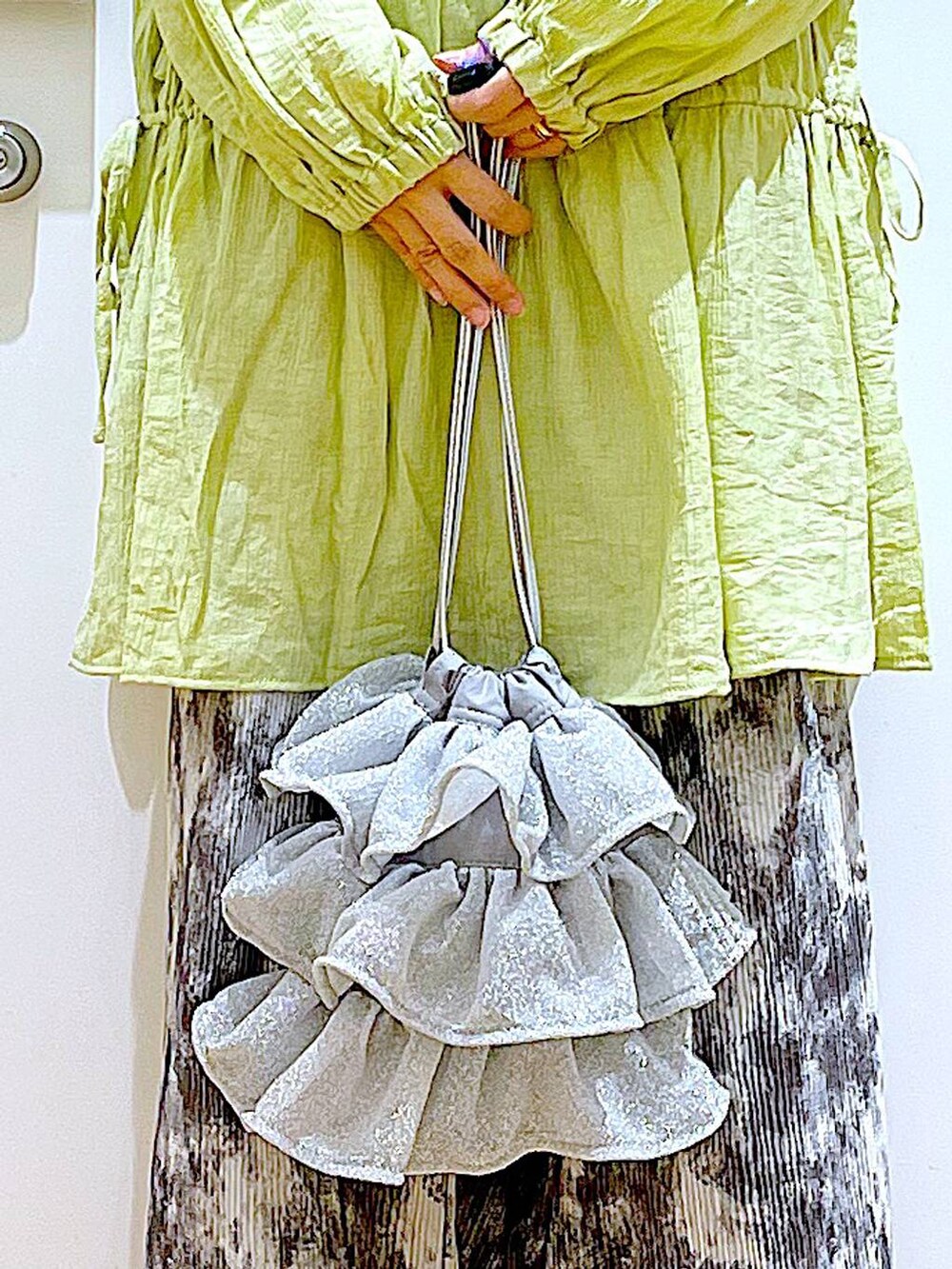 シルバー系のショルダーバッグ、シルバー系のパンプス、グリーン系のチュニックを着用したレディースの春コーディネートの9枚目の写真