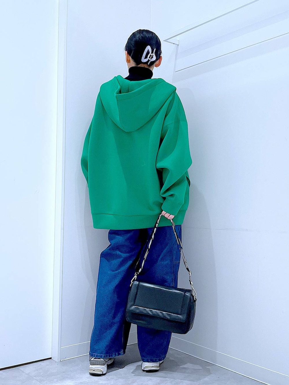 ブラック系のショルダーバッグ、ブラック系のニット/セーター、ブルー系のデニムパンツを着用したレディースの冬コーディネートの5枚目の写真