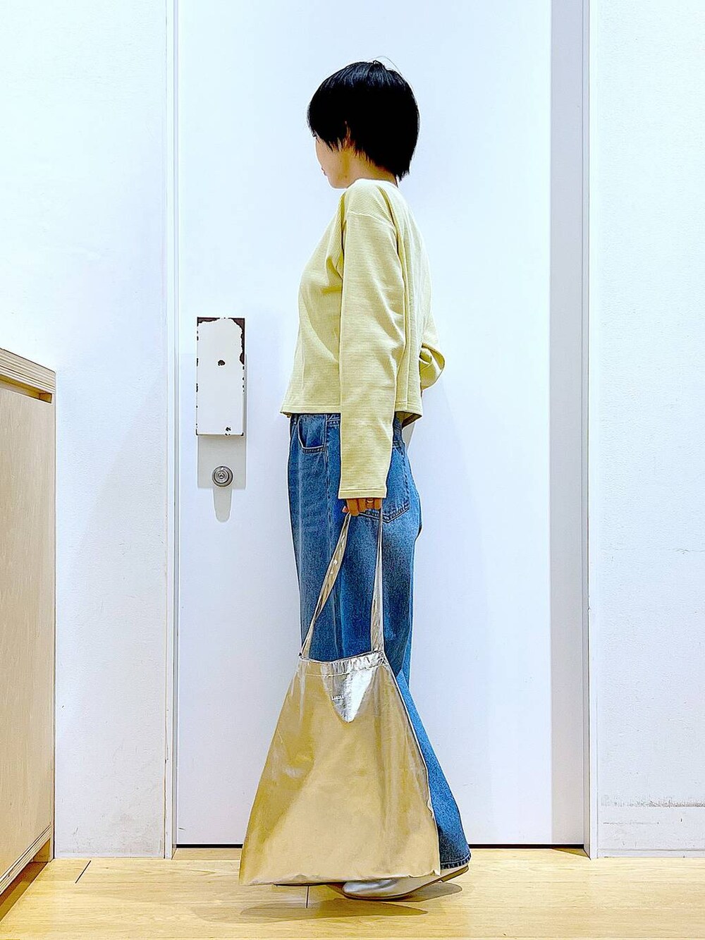 シルバー系のトートバッグ、ブルー系のデニムパンツ、シルバー系のパンプスを着用したレディースの春コーディネートの3枚目の写真