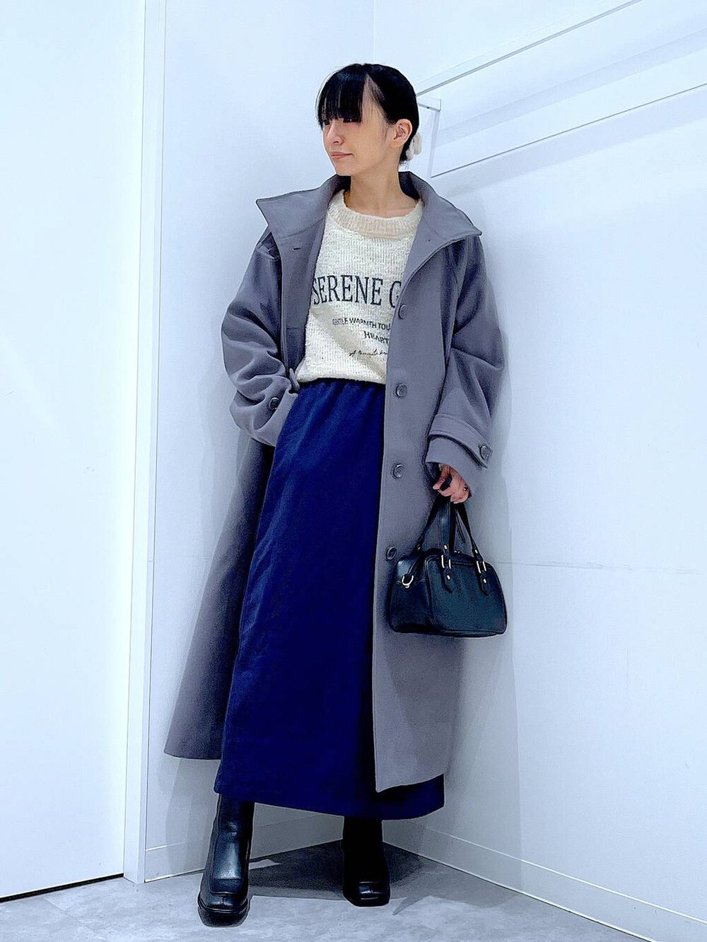 グレー系のその他アウター、ホワイト系のニット/セーター、ブルー系のスカートを着用したレディースの秋コーディネートの2枚目の写真