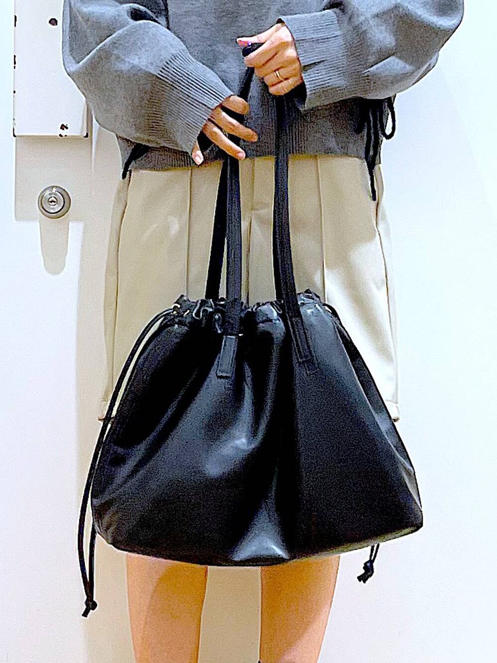 ブラック系のトートバッグ、ブラック系のブーツ、グレー系のニット/セーターを着用したレディースの冬コーディネートの9枚目の写真