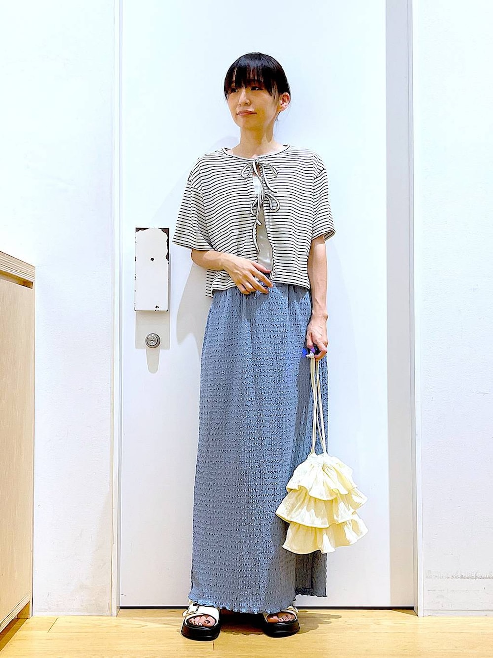 ホワイト系のサンダル、ブルー系のスカート、ホワイト系のショルダーバッグを着用したレディースの秋コーディネートの2枚目の写真