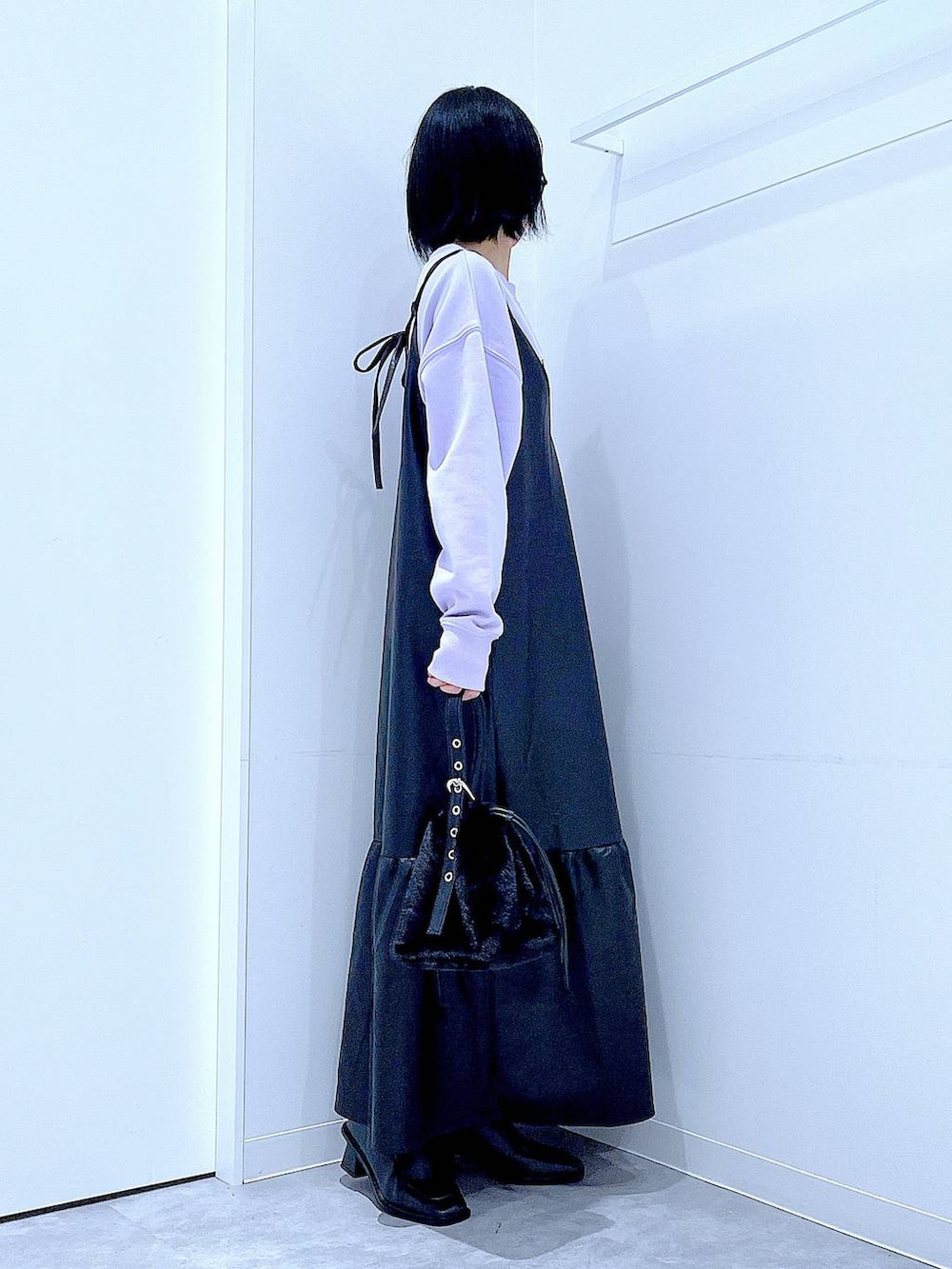 ブラック系のハンドバッグ、ブラック系のブーツ、パープル系のスウェットを着用したレディースの冬コーディネートの4枚目の写真