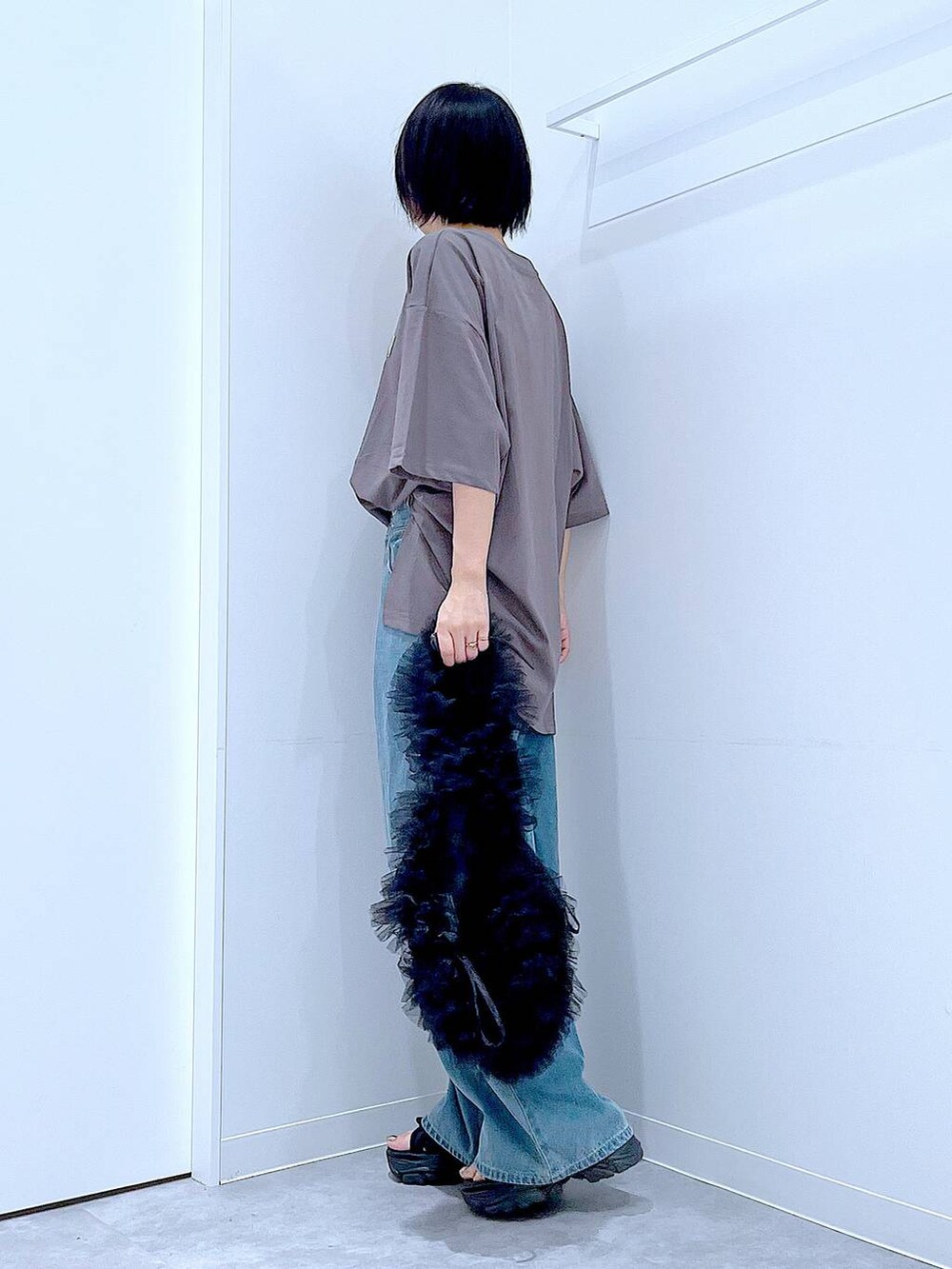 ブラック系のショルダーバッグ、ブラック系のスニーカー、ブルー系のデニムパンツを着用したレディースの秋コーディネートの3枚目の写真