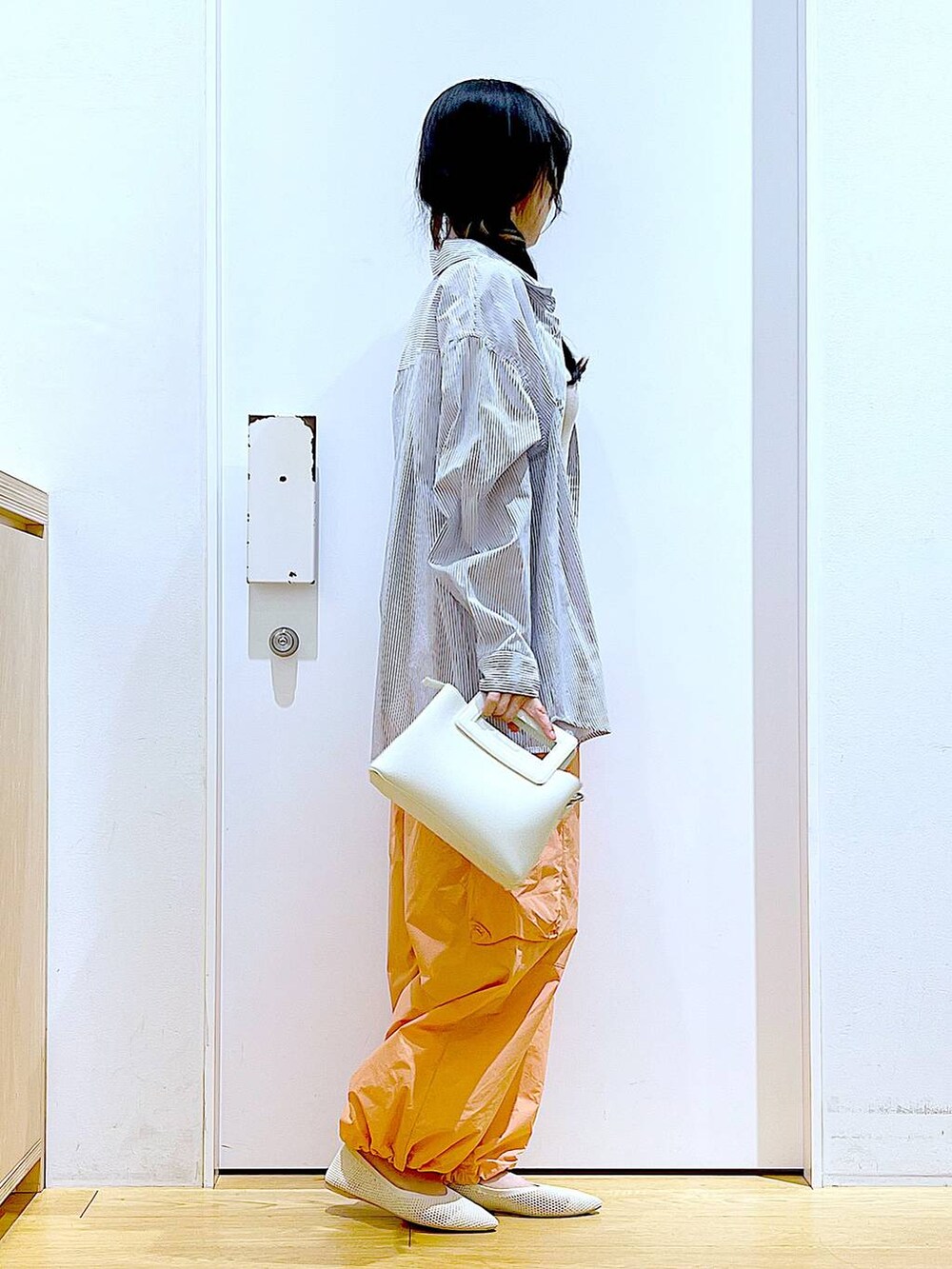 ホワイト系のシャツ/ブラウス、イエロー系のニット/セーター、ホワイト系のショルダーバッグを着用したレディースの春コーディネートの4枚目の写真