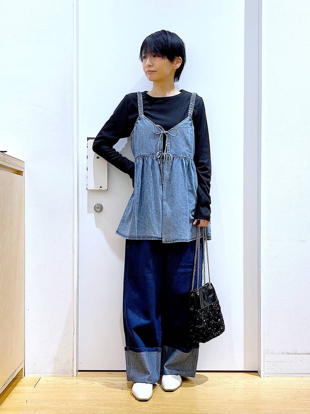 ホワイト系のパンプス、ブルー系のデニムパンツ、ブラック系のショルダーバッグを着用したレディースの春コーディネートの2枚目の写真