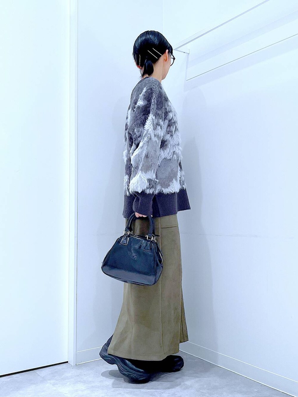 ブラック系のブーツ、ブラック系のニット/セーター、ブラック系のショルダーバッグを着用したレディースの冬コーディネートの4枚目の写真