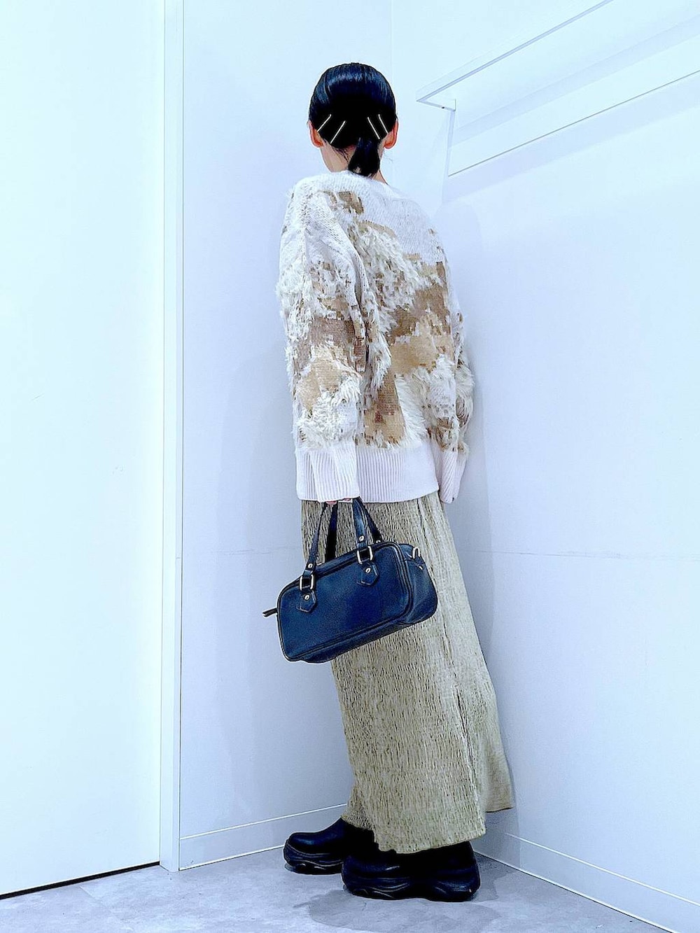 ブラック系のブーツ、ブラック系のショルダーバッグ、グリーン系のスカートを着用したレディースの冬コーディネートの3枚目の写真