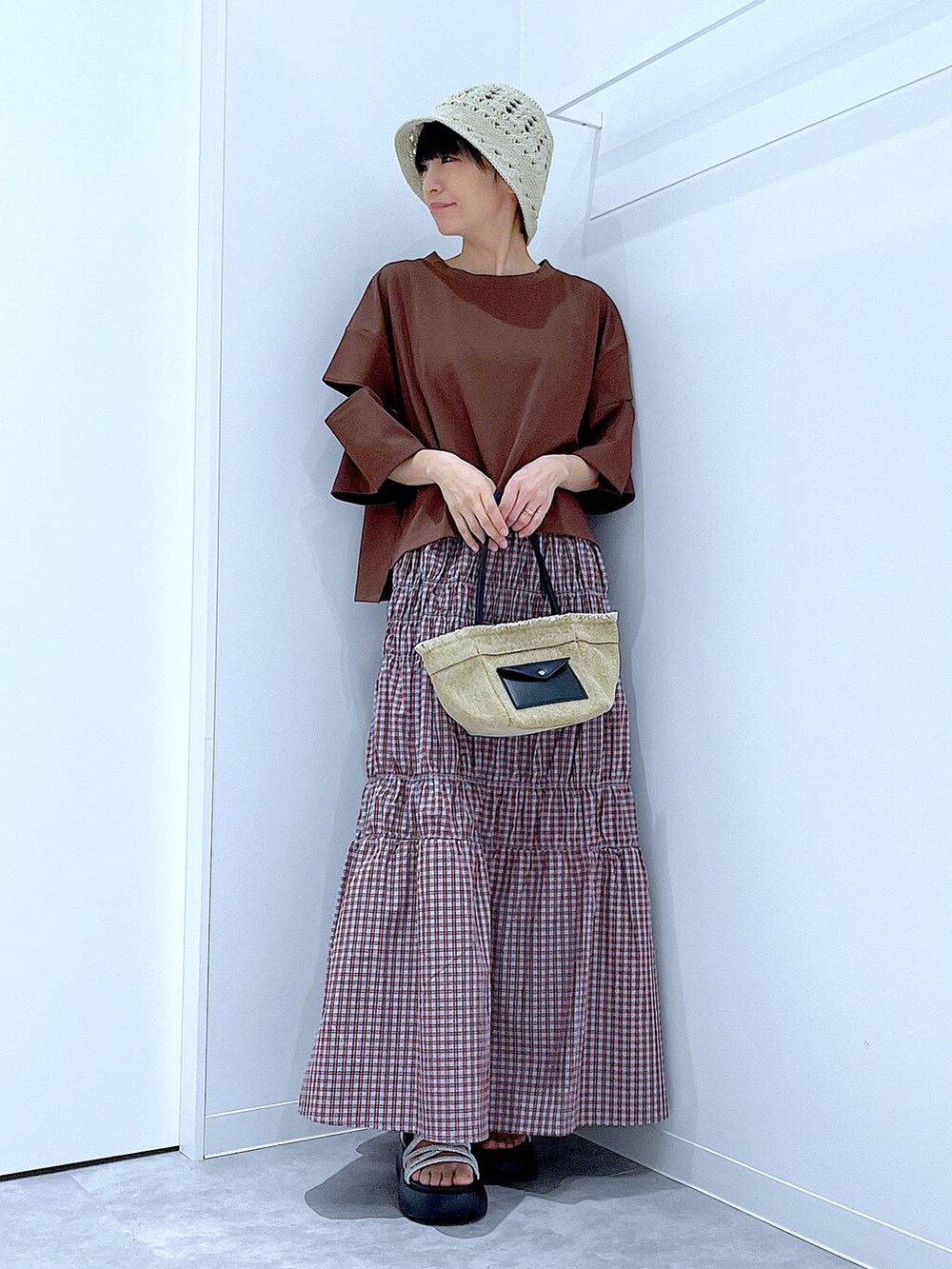 ベージュ系のショルダーバッグ、シルバー系のサンダル、ブラウン系のTシャツ/カットソーを着用したレディースの夏コーディネートの2枚目の写真