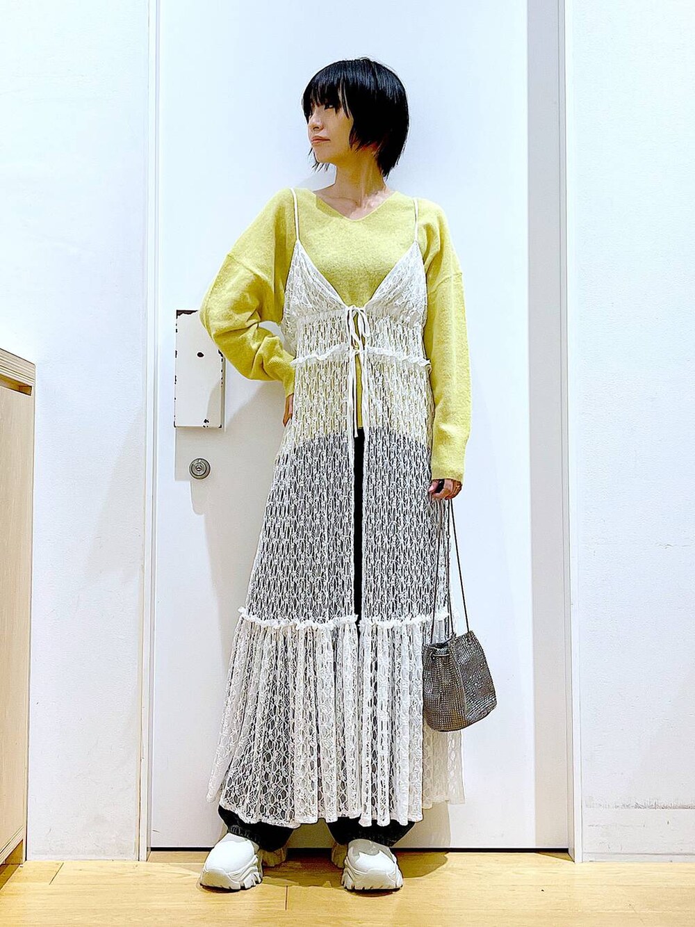 イエロー系のニット/セーター、グレー系のショルダーバッグ、ホワイト系のワンピースを着用したレディースの冬コーディネートの2枚目の写真