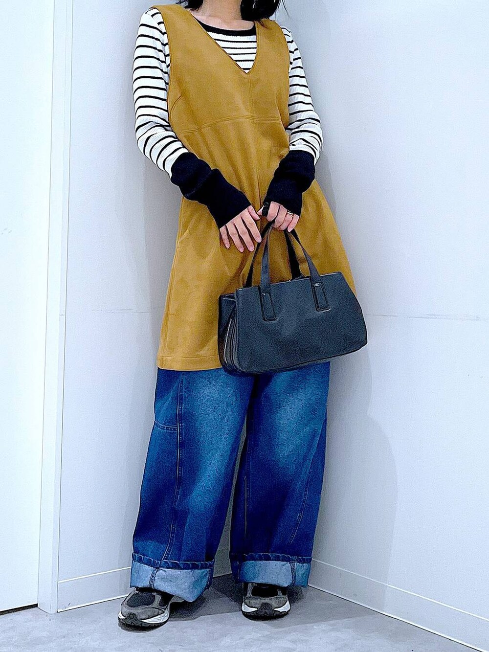 ブラック系のボストンバッグ、ホワイト系のニット/セーター、イエロー系のワンピースを着用したレディースの春コーディネートの6枚目の写真