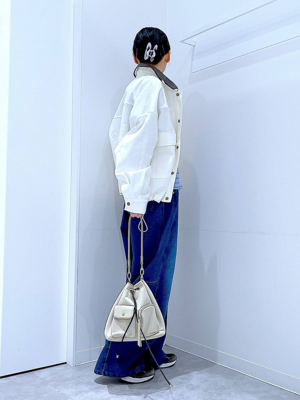 ブルー系のニット/セーター、ブルー系のデニムパンツ、ベージュ系のブルゾンを着用したレディースの冬コーディネートの4枚目の写真