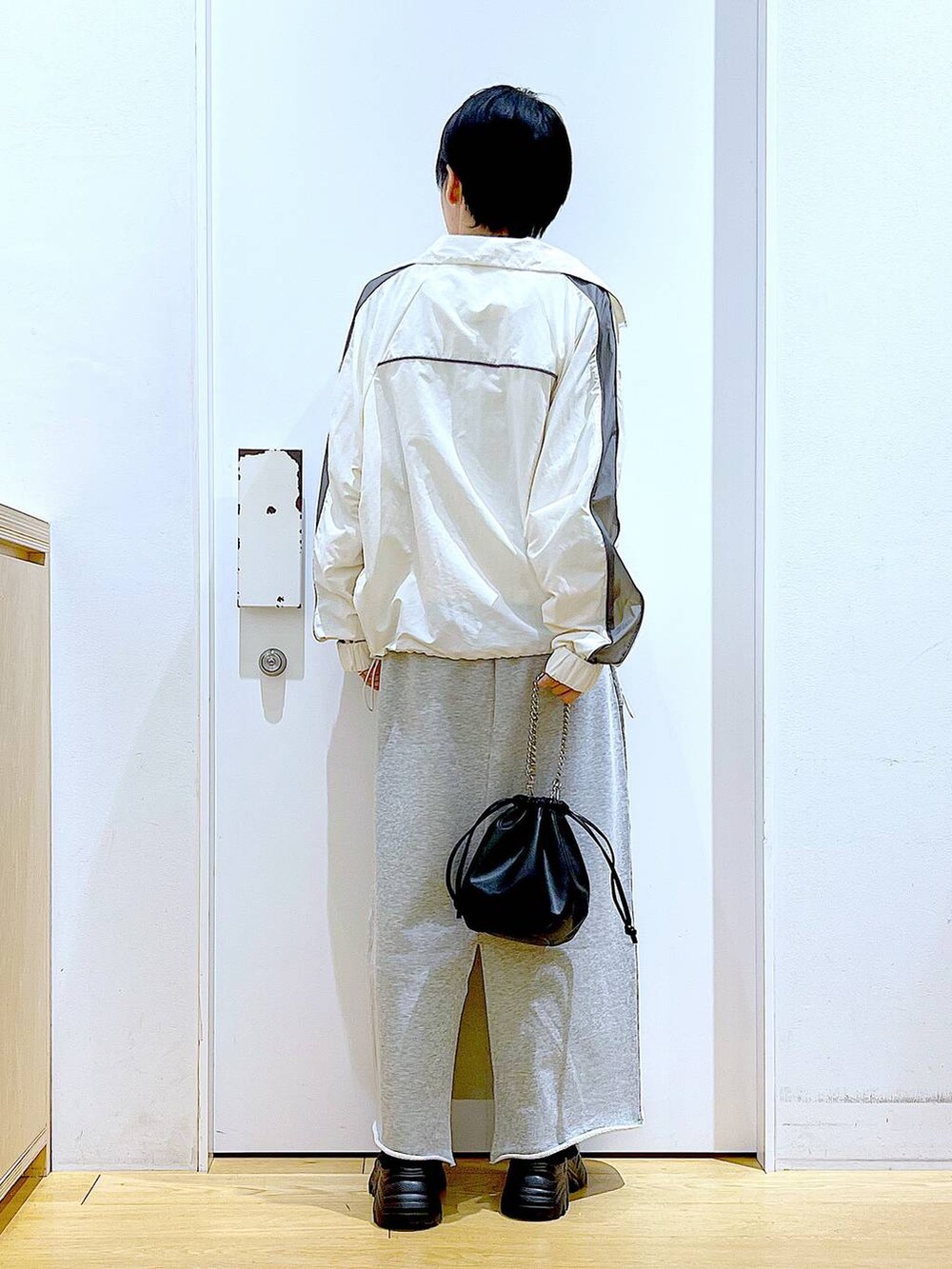 ブラック系のブーツ、ブラック系のショルダーバッグ、グレー系のスカートを着用したレディースの春コーディネートの5枚目の写真