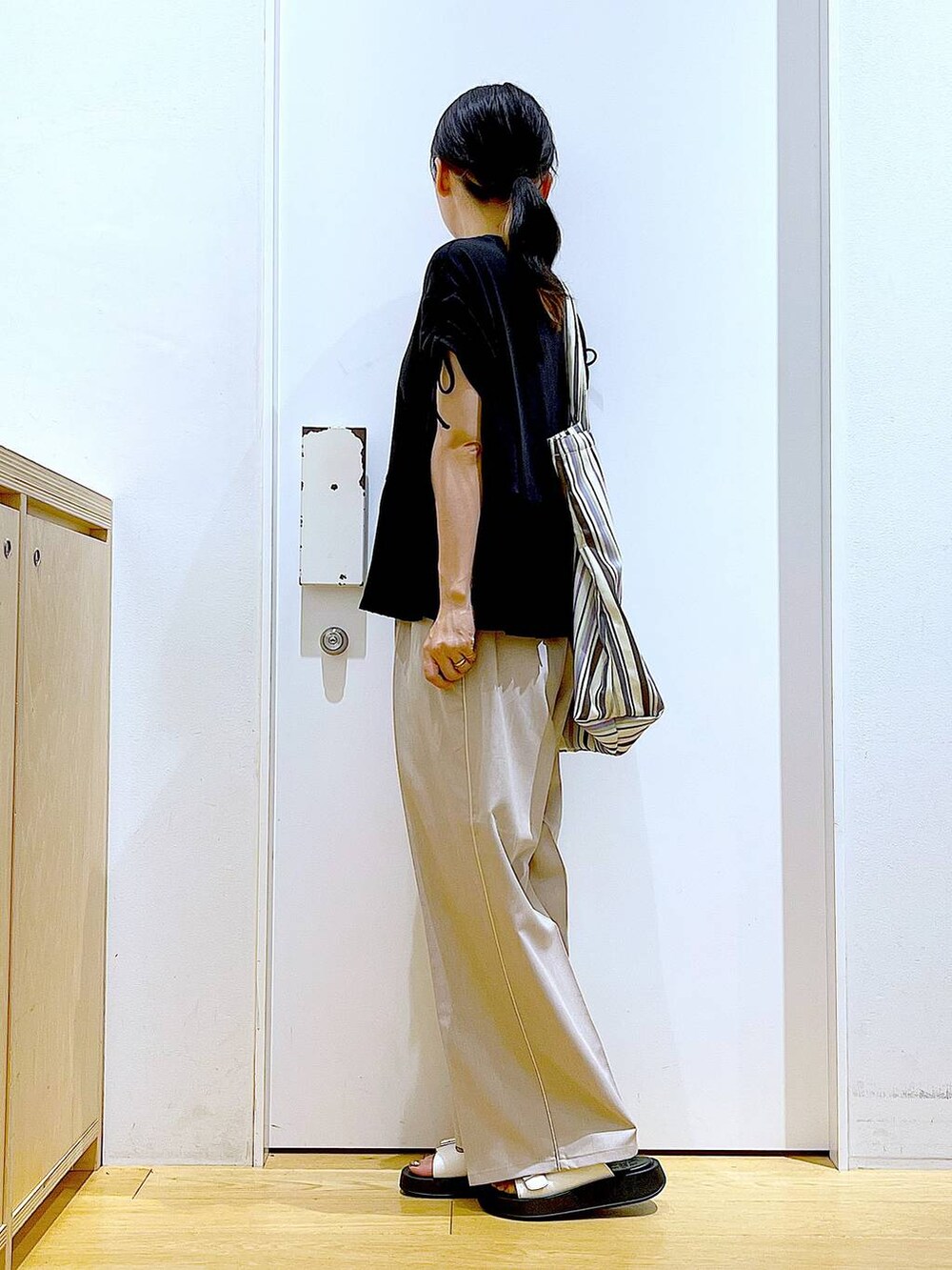 ホワイト系のサンダル、グリーン系のトートバッグ、ベージュ系のスラックスを着用したレディースの秋コーディネートの3枚目の写真