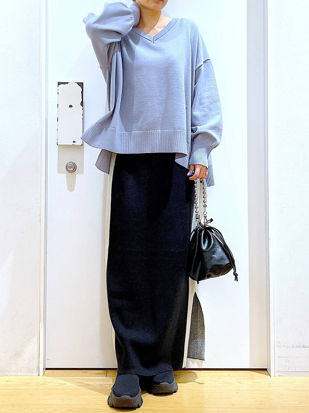 ブラック系のスカート、ブラック系のショルダーバッグ、ブラック系のブーツを着用したレディースの冬コーディネートの6枚目の写真