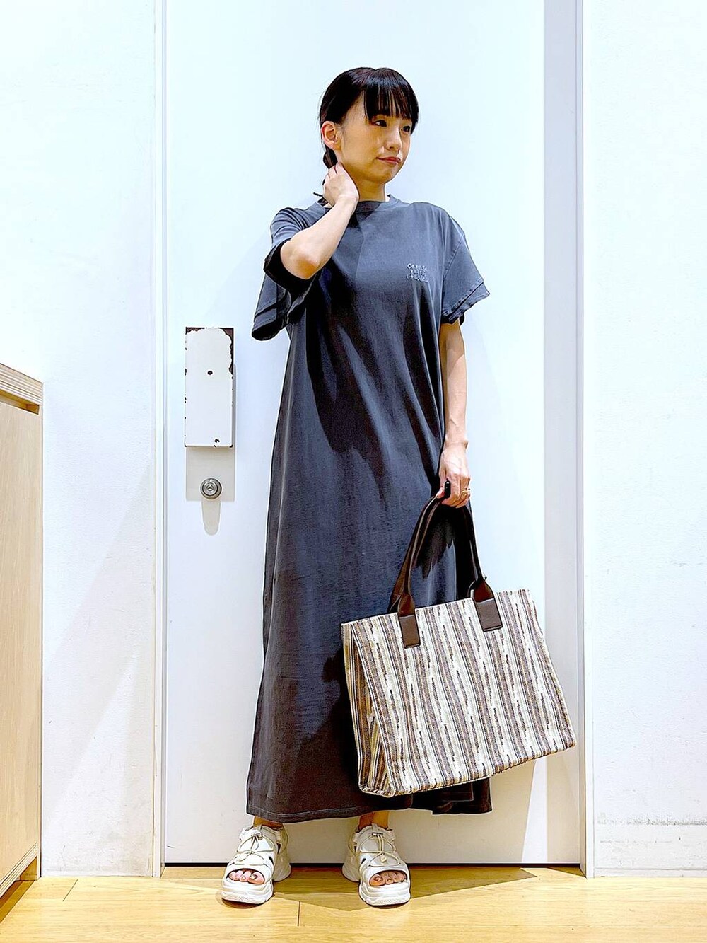 ホワイト系のサンダル、ブラウン系のトートバッグ、グレー系のワンピースを着用したレディースの夏コーディネートの2枚目の写真