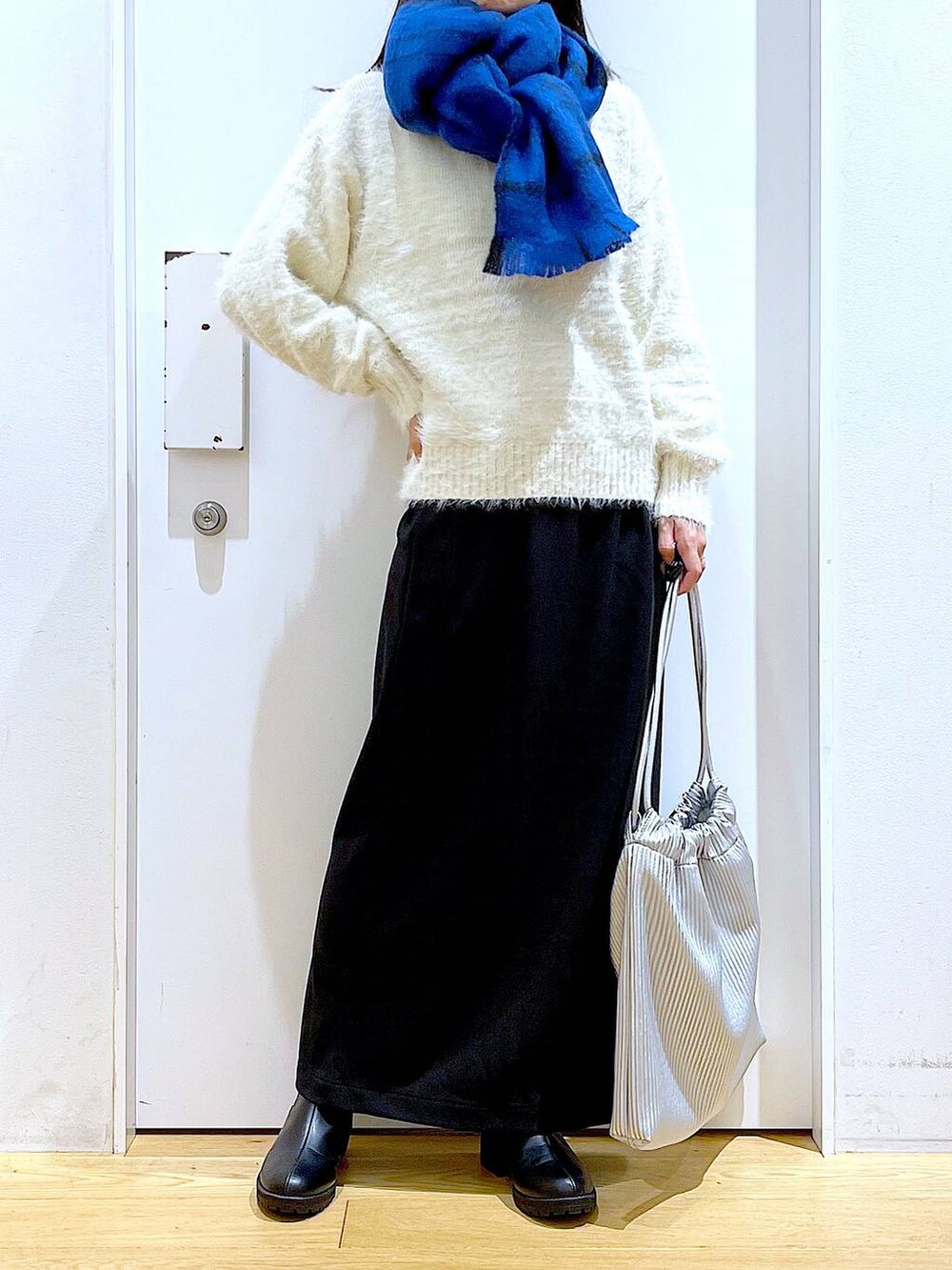 ブラック系のブーツ、シルバー系のトートバッグ、ベージュ系のニット/セーターを着用したレディースの冬コーディネートの6枚目の写真