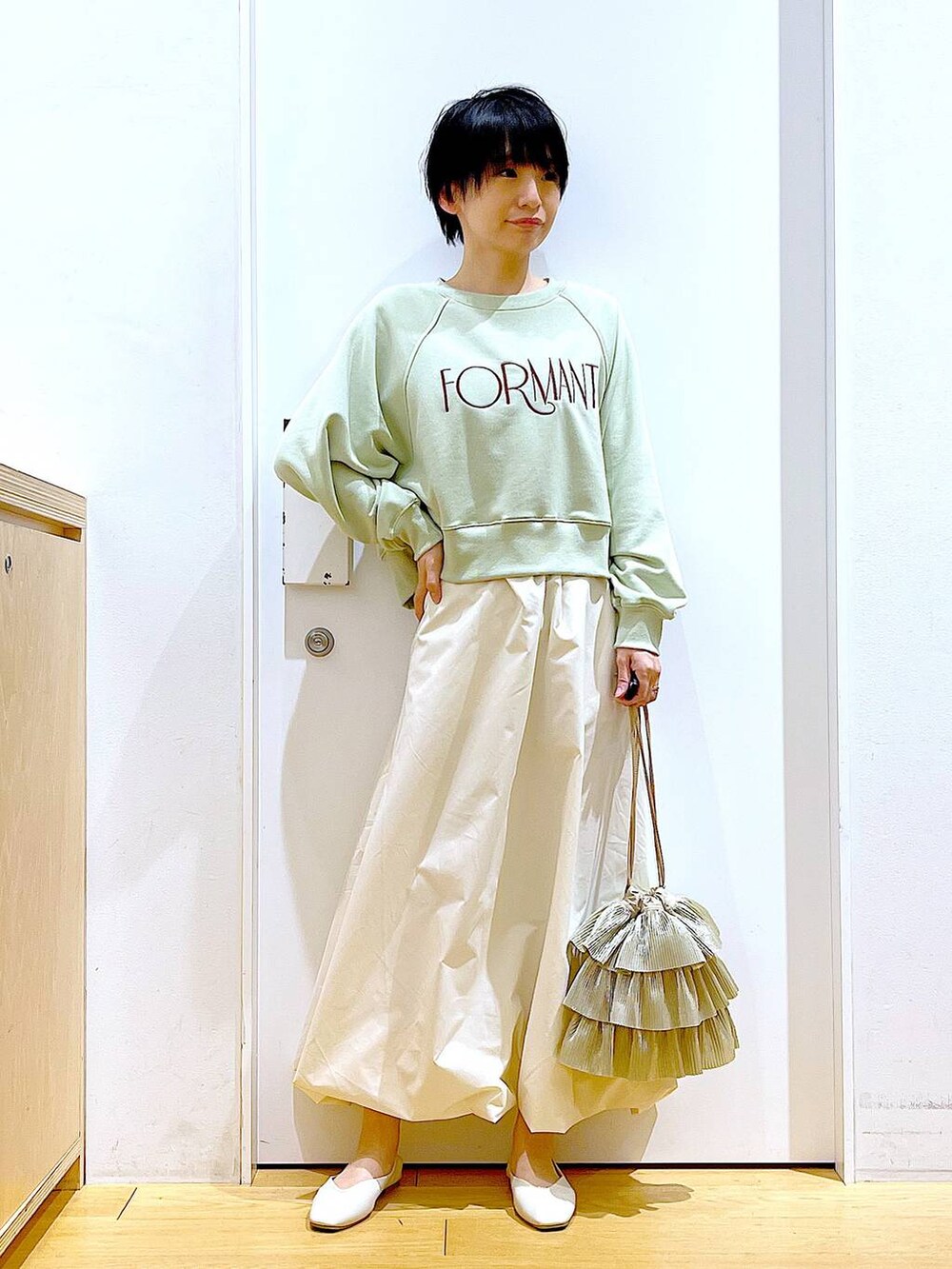 ホワイト系のパンプス、ベージュ系のショルダーバッグ、グリーン系のスウェットを着用したレディースの春コーディネートの2枚目の写真