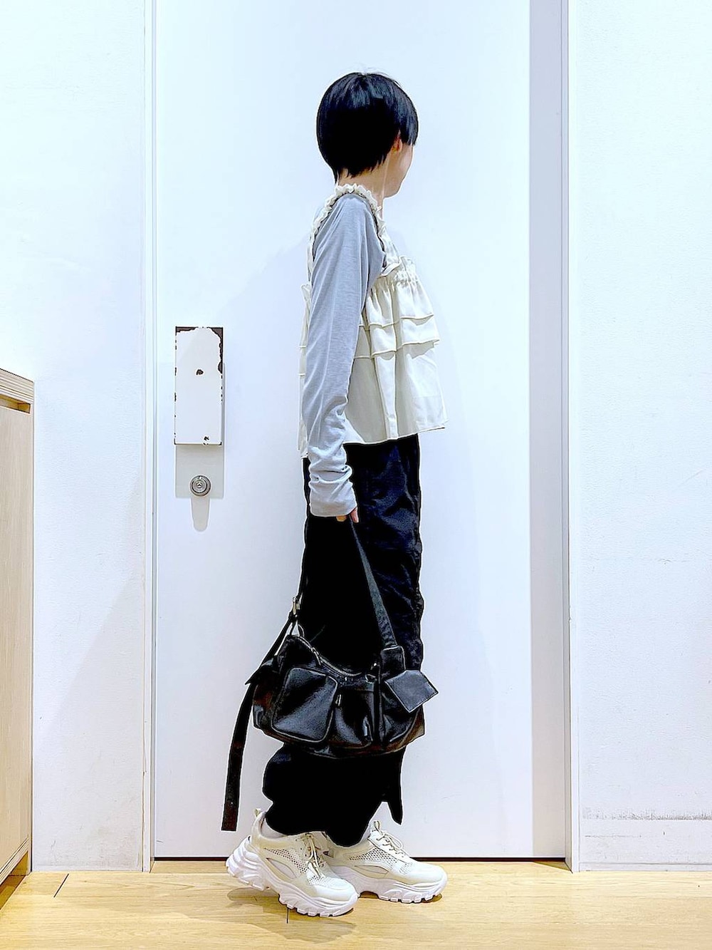 ブラック系のスカート、ブラック系のショルダーバッグ、ホワイト系のスニーカーを着用したレディースの春コーディネートの4枚目の写真