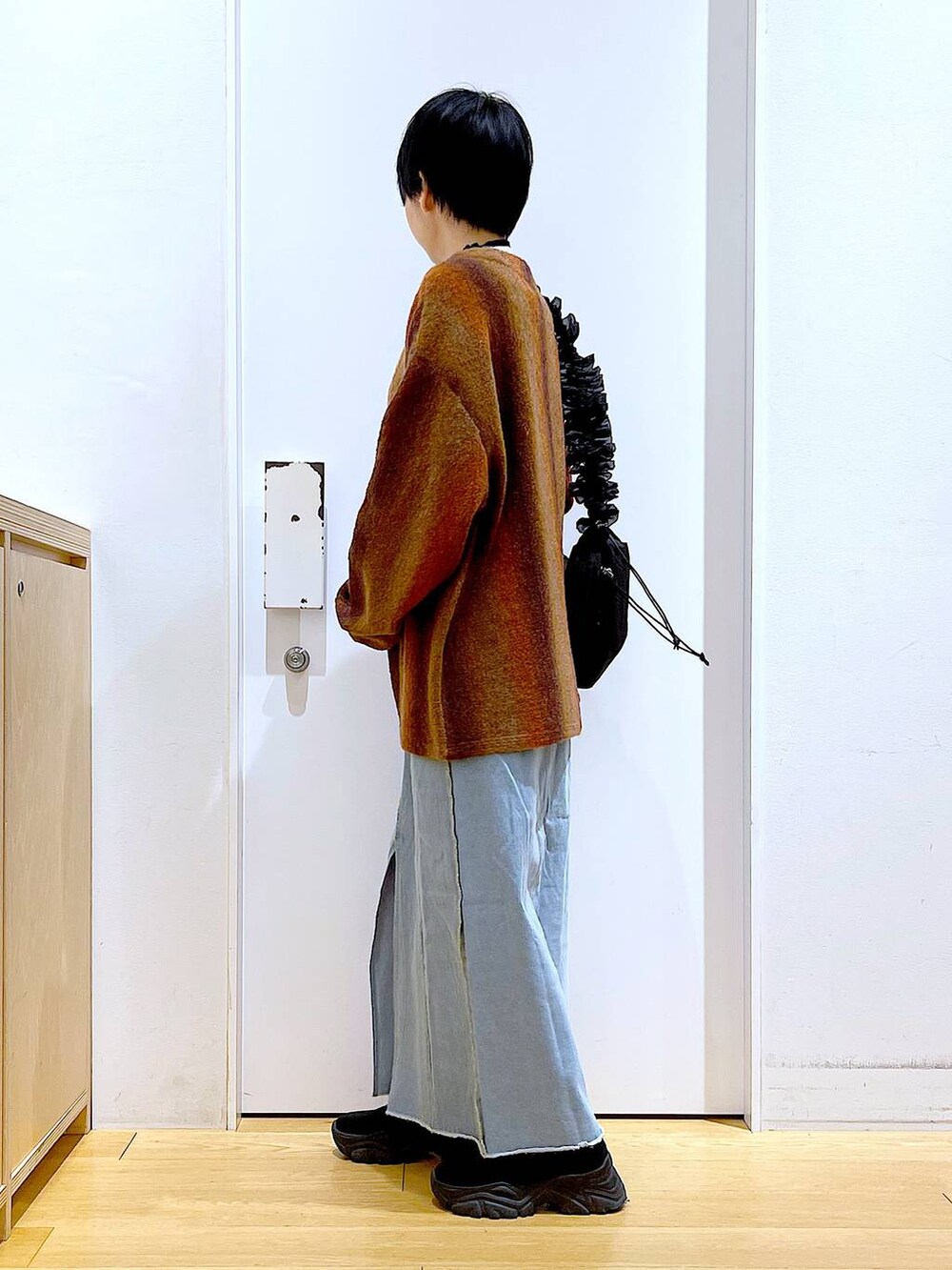 ベージュ系のニット/セーター、ブラック系のショルダーバッグ、ブルー系のデニムスカートを着用したレディースの冬コーディネートの3枚目の写真
