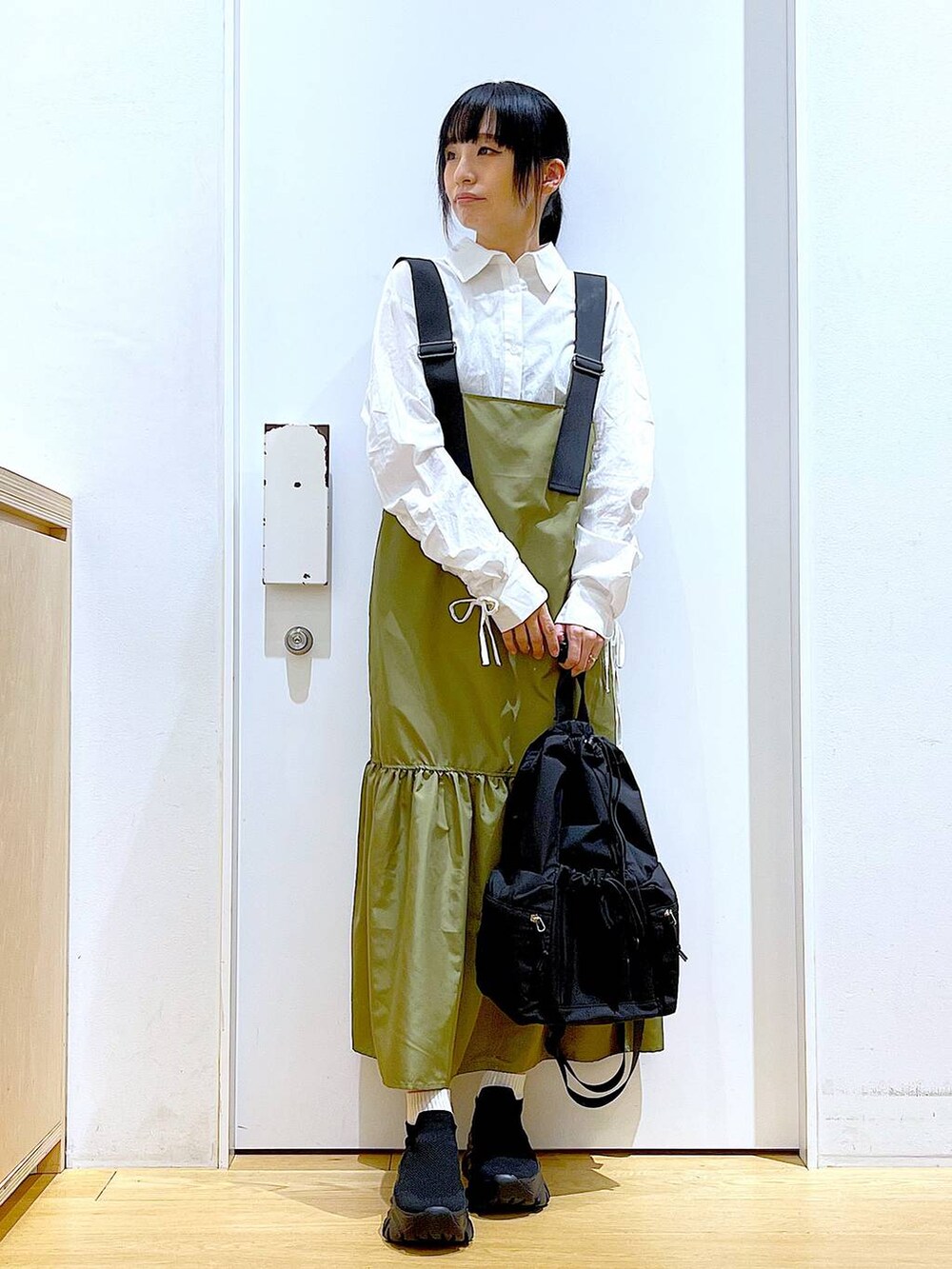 ブラック系のショルダーバッグ、グリーン系のワンピース、ホワイト系のシャツ/ブラウスを着用したレディースの春コーディネートの2枚目の写真