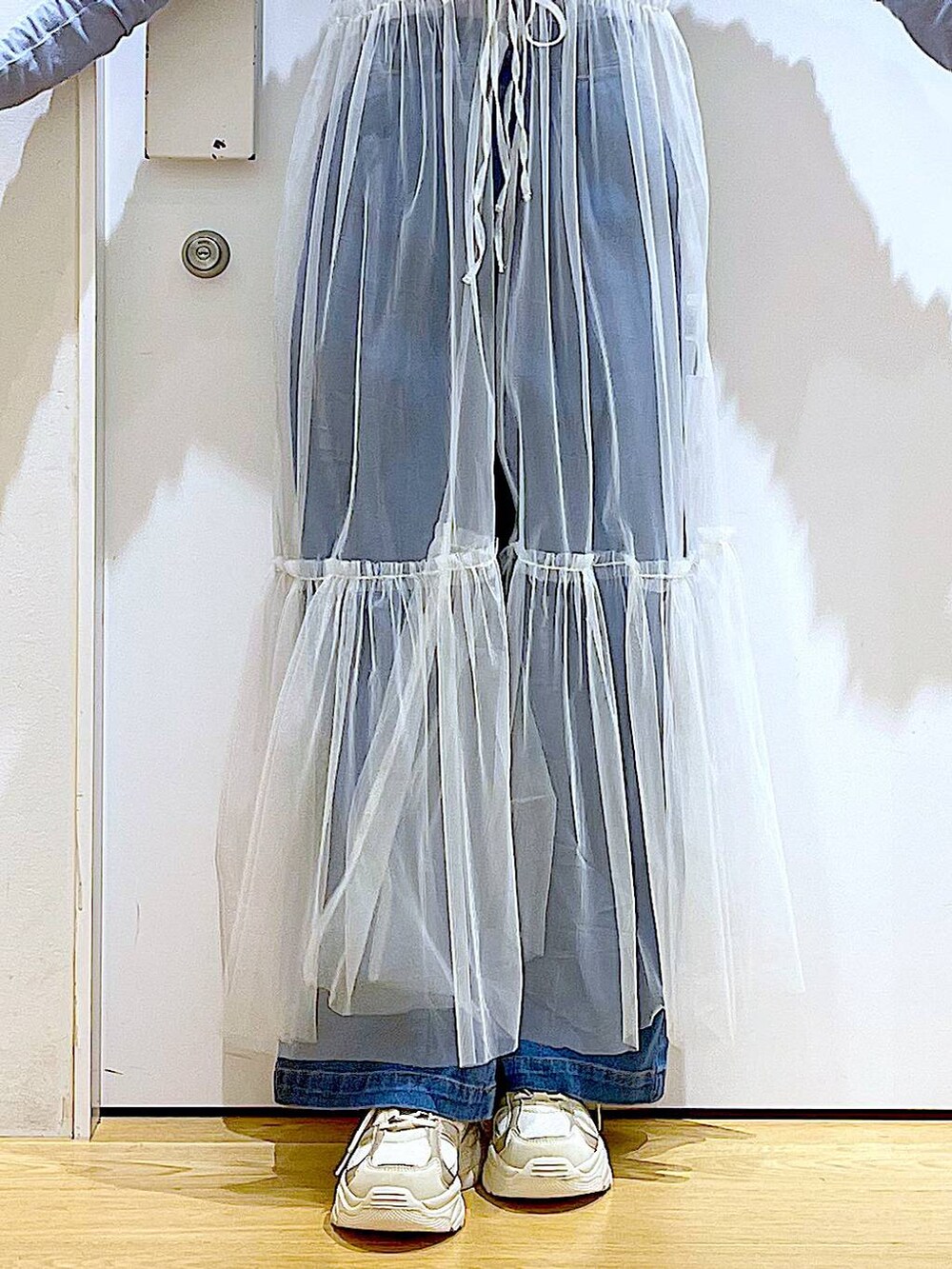 ブルー系のデニムパンツ、ホワイト系のワンピース、ベージュ系のスニーカーを着用したレディースの冬コーディネートの8枚目の写真