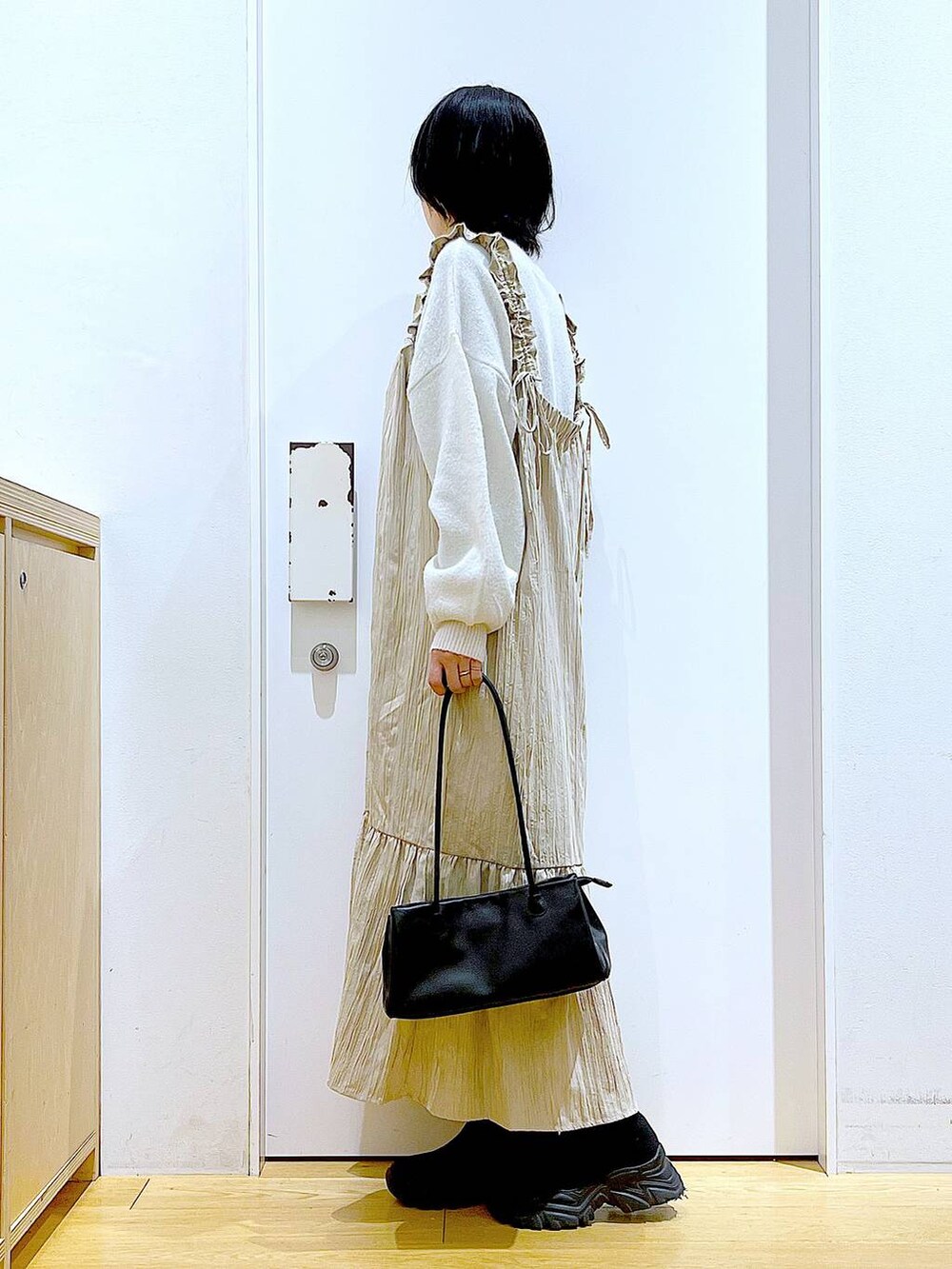 ブラック系のブーツ、ブラック系のトートバッグ、ベージュ系のニット/セーターを着用したレディースの冬コーディネートの3枚目の写真