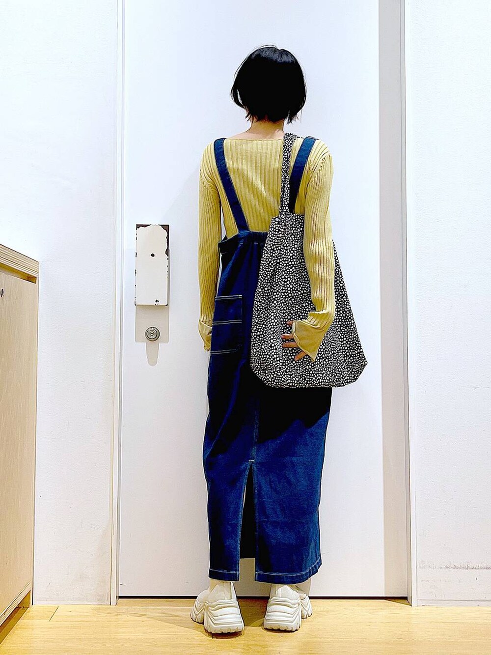 ブルー系のジャンパースカート、ブラック系のトートバッグ、イエロー系のニット/セーターを着用したレディースの秋コーディネートの5枚目の写真