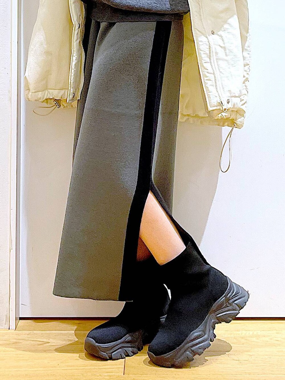 グレー系のスカート、ブラック系のブーツ、ホワイト系のその他アウターを着用したレディースの冬コーディネートの8枚目の写真