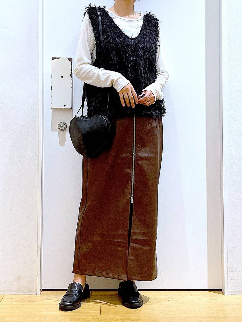 ブラウン系のスカート、ブラック系のショルダーバッグ、ホワイト系のTシャツ/カットソーを着用したレディースの秋コーディネートの6枚目の写真