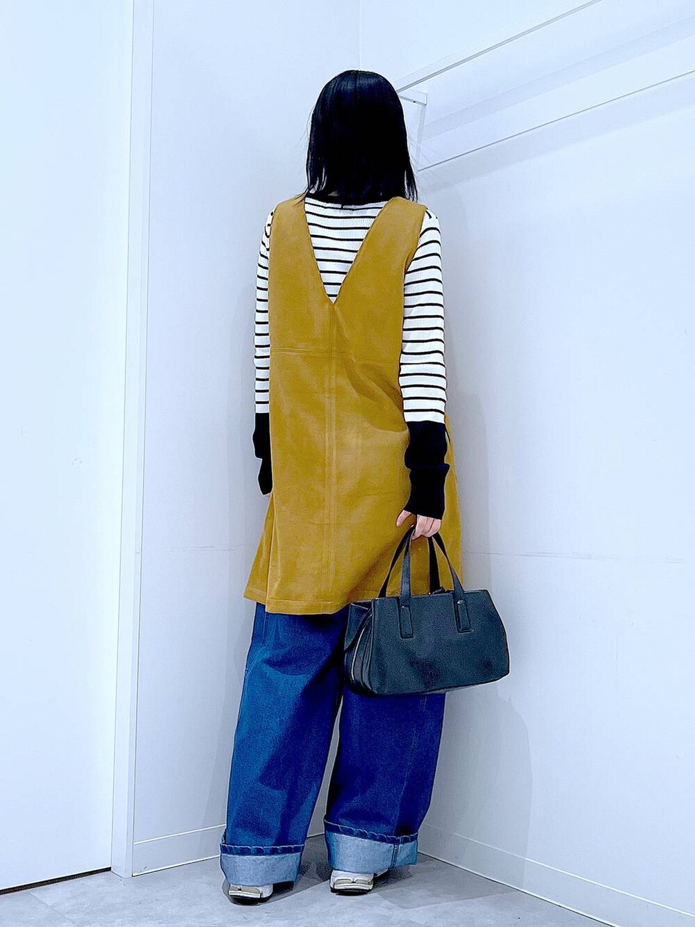 ブラック系のボストンバッグ、ホワイト系のニット/セーター、イエロー系のワンピースを着用したレディースの春コーディネートの5枚目の写真