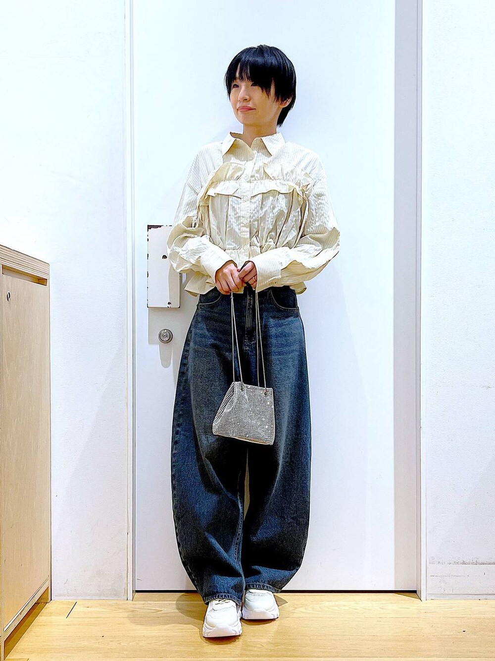 グレー系のショルダーバッグ、ブルー系のデニムパンツ、ホワイト系のスニーカーを着用したレディースの春コーディネートの2枚目の写真