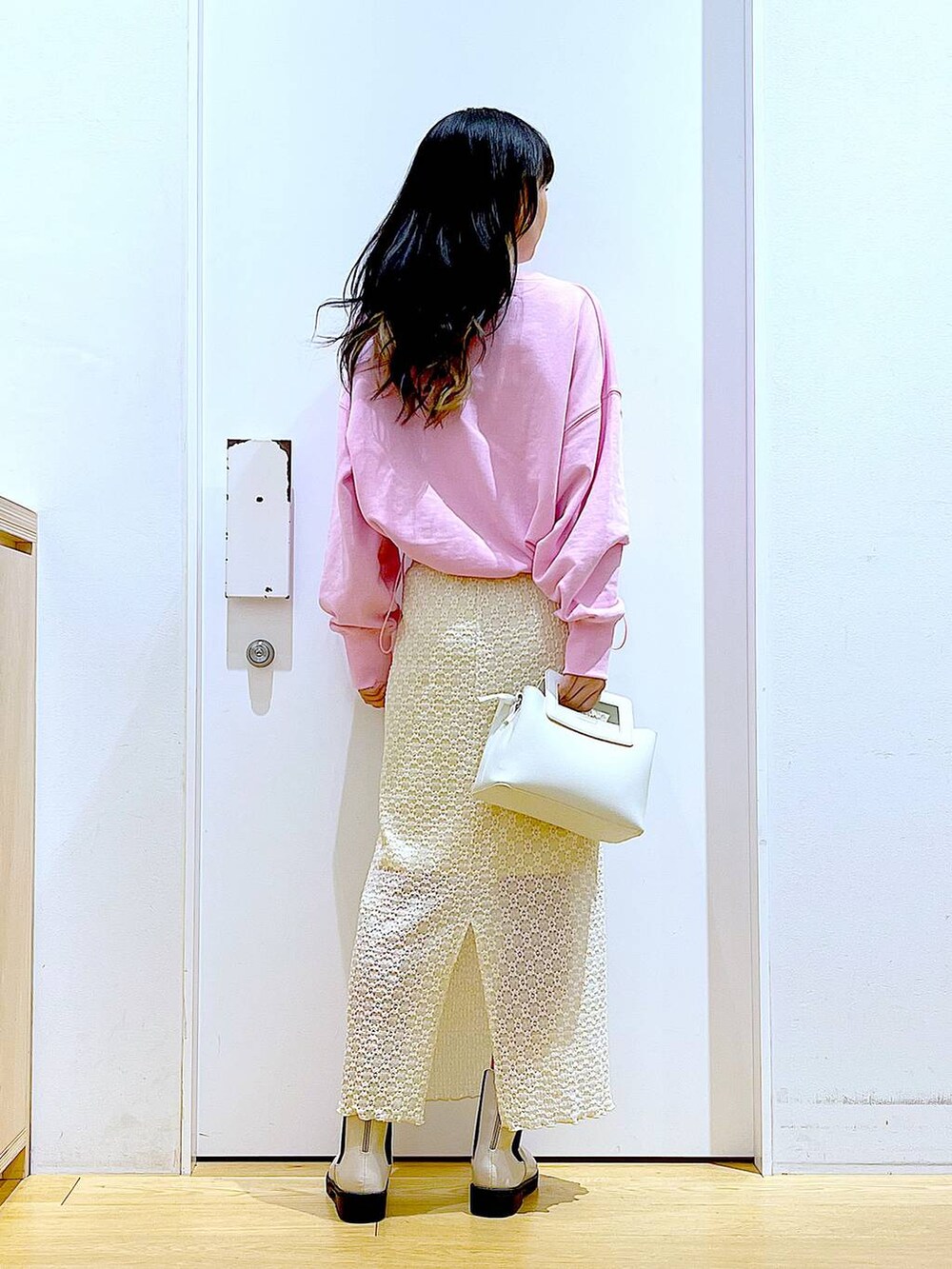 ピンク系のスウェット、ベージュ系のブーツ、ホワイト系のショルダーバッグを着用したレディースの春コーディネートの5枚目の写真