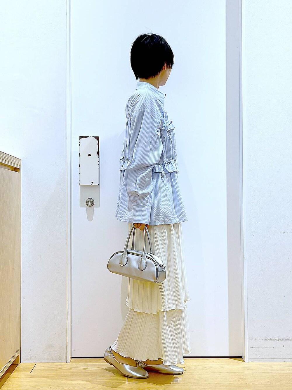 シルバー系のボストンバッグ、シルバー系のパンプス、ブルー系のシャツ/ブラウスを着用したレディースの春コーディネートの4枚目の写真