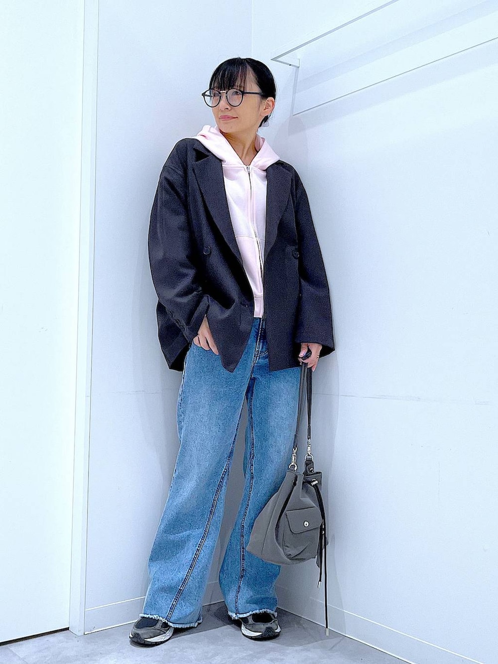 グレー系のテーラードジャケット、ブルー系のデニムパンツ、ピンク系のパーカーを着用したレディースの春コーディネートの2枚目の写真