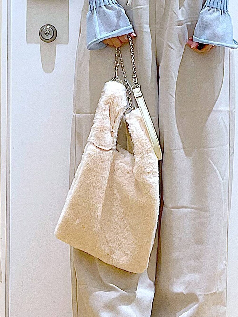 ブルー系のニット/セーター、ホワイト系のショルダーバッグ、ベージュ系のブーツを着用したレディースの冬コーディネートの9枚目の写真