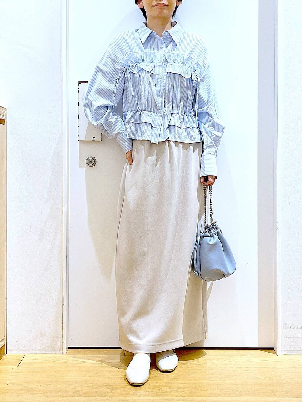 ブルー系のショルダーバッグ、ホワイト系のパンプス、ベージュ系のスカートを着用したレディースの春コーディネートの6枚目の写真