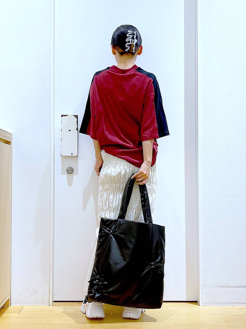 ホワイト系のスカート、ブラック系のスニーカー、ブラック系のトートバッグを着用したレディースの秋コーディネートの5枚目の写真