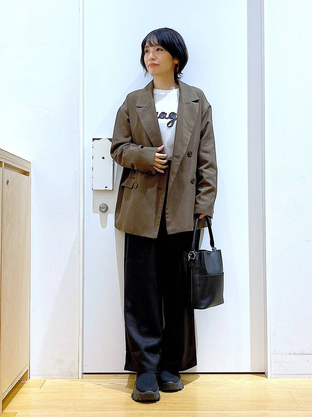 ブラック系のブーツ、ブラック系のショルダーバッグ、ブラウン系のテーラードジャケットを着用したレディースの秋コーディネートの2枚目の写真