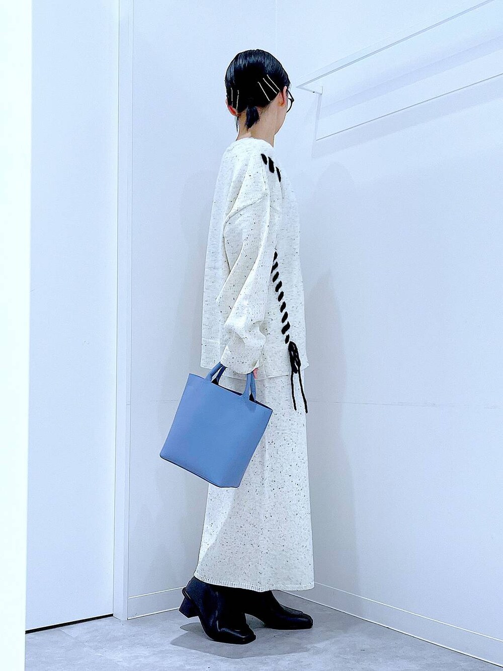 ブルー系のショルダーバッグ、ホワイト系のニット/セーター、ベージュ系のスカートを着用したレディースの秋コーディネートの4枚目の写真