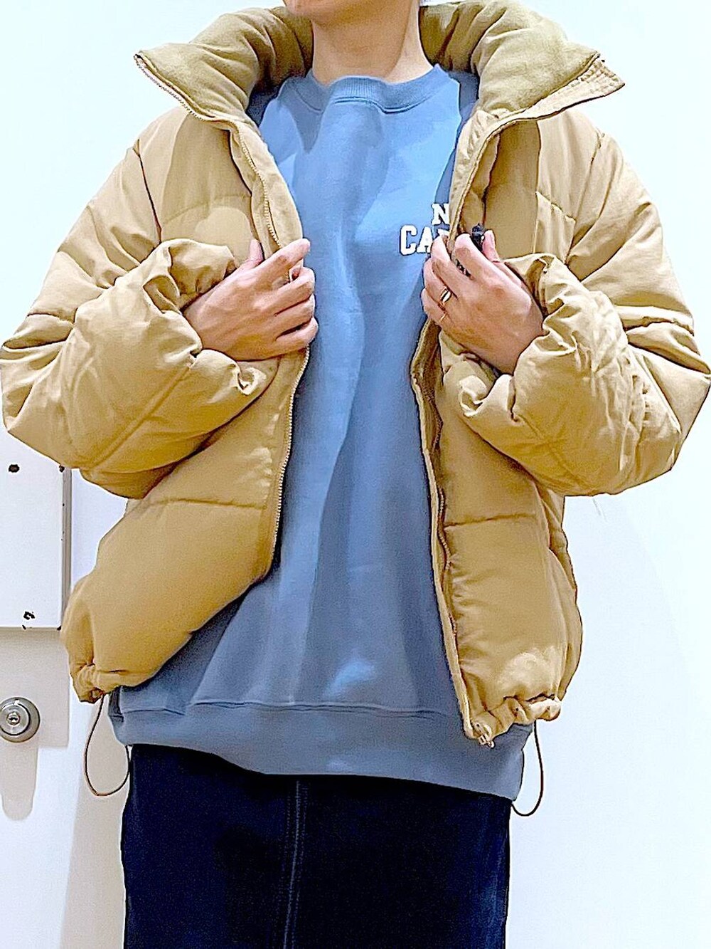 シルバー系のトートバッグ、ベージュ系のナイロンジャケット、ブルー系のデニムスカートを着用したレディースの冬コーディネートの7枚目の写真