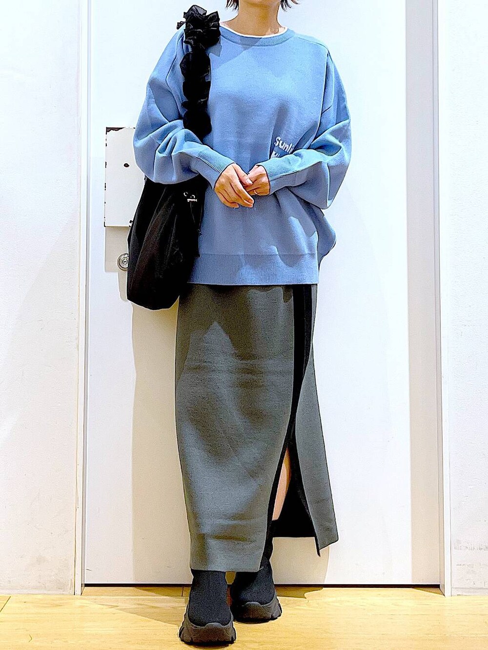 ブルー系のニット/セーター、ブラック系のショルダーバッグ、グレー系のスカートを着用したレディースの冬コーディネートの6枚目の写真