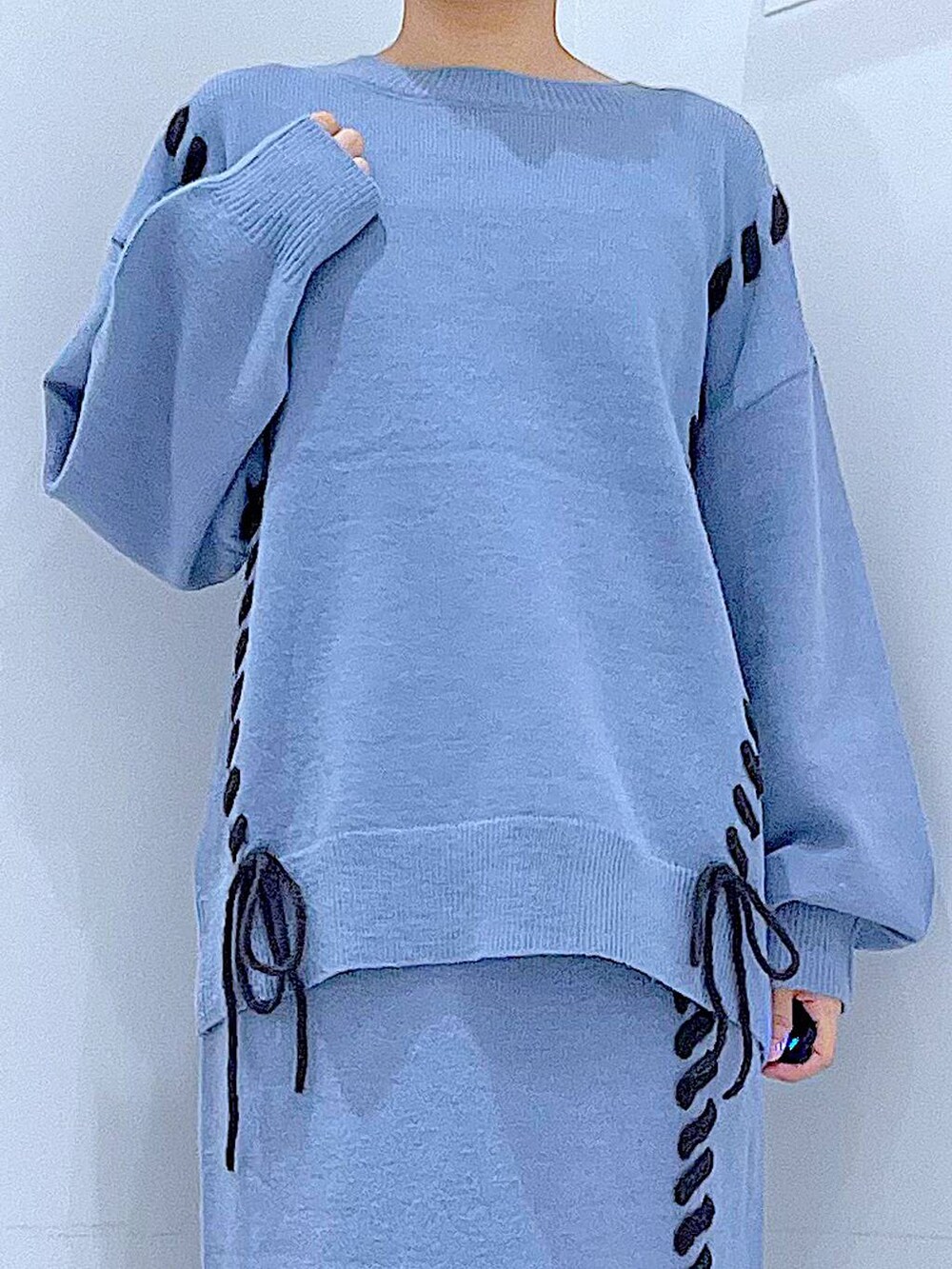 ブルー系のニット/セーター、ブルー系のスカート、ブラック系のブーツを着用したレディースの秋コーディネートの7枚目の写真